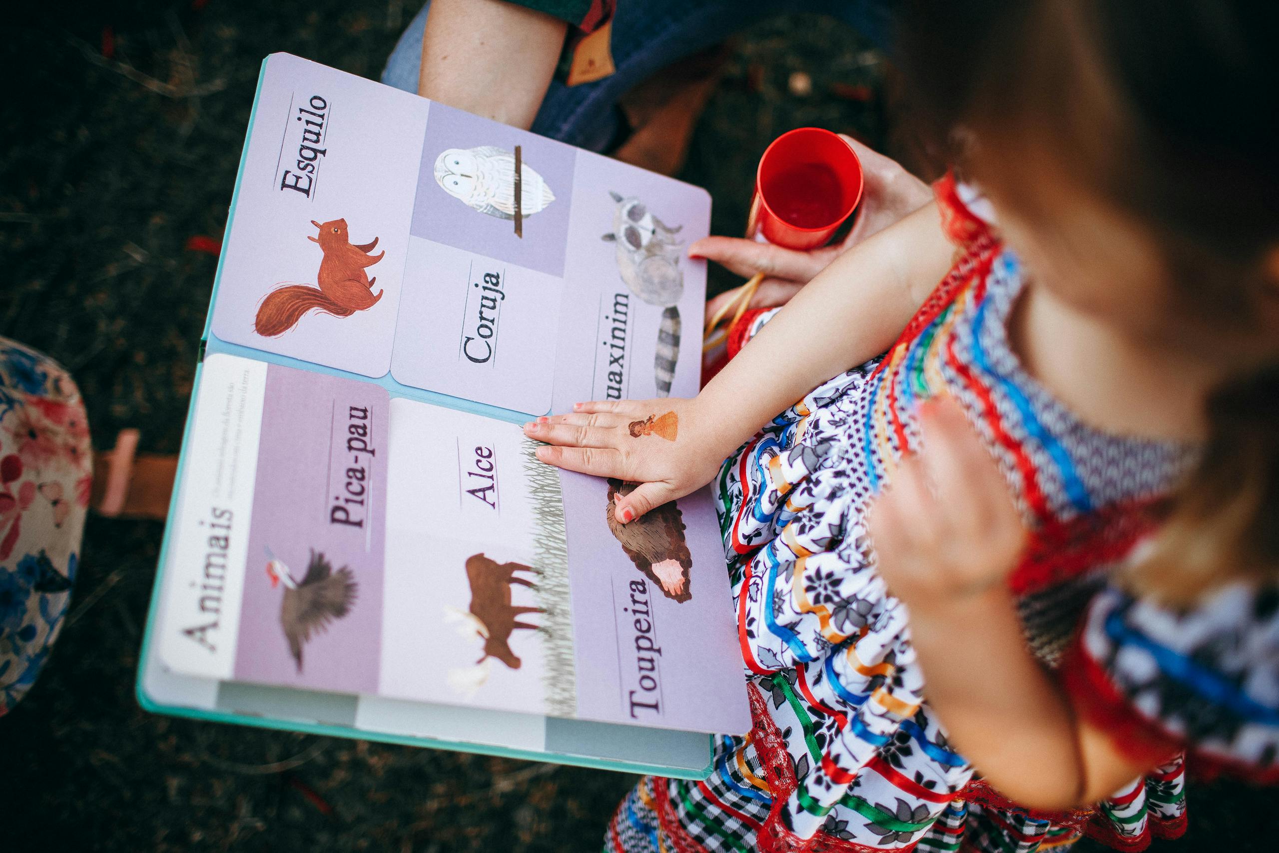 Child reading book with mother in garden